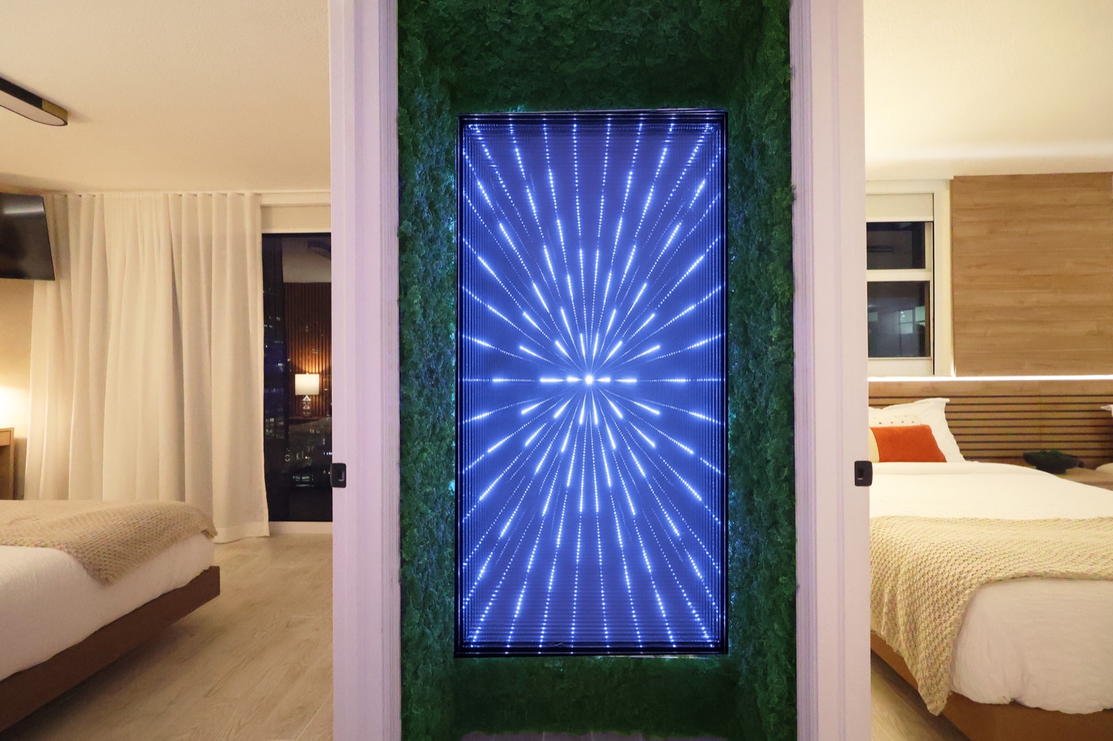 Infinity-mirror LED feature wall with blue starburst lighting between the two bedrooms